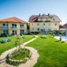 Gartenanlage Dorfhotel Grüner Baum, © Photography Pfeffel Gartenanlage mit gelben Gebäuden und Liegestühlen bei sonnigem Wetter.
