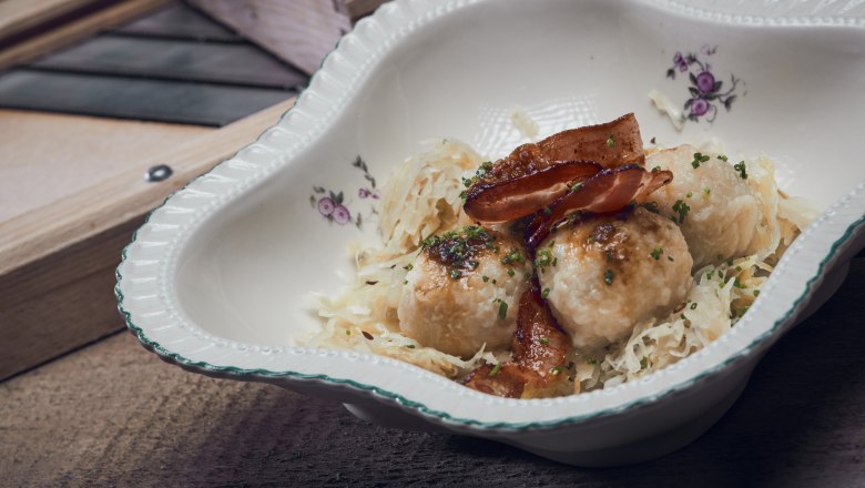 Knödel mit Kraut, © Niederösterreich Werbung/Andreas Hofer Traditionelles Gericht mit Knödeln, Speck und Sauerkraut in dekorativer Schale.