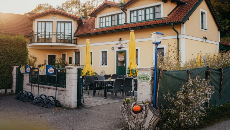 Located directly on the Danube cycle path, © Niederösterreich Werbung/Daniela Führer Restaurant with terrace, yellow parasols and floral decor.