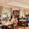 Old shipmaster's house, © Best fo Wachau_Rita Newman A cozy restaurant with guests dining at tables. A waiter serves the guests. Window with a view of a green landscape.