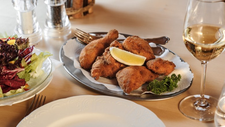 Restaurant enjoyment, © Roman Siebenhandl A plate of breaded chicken, salad and a glass of white wine on a table.