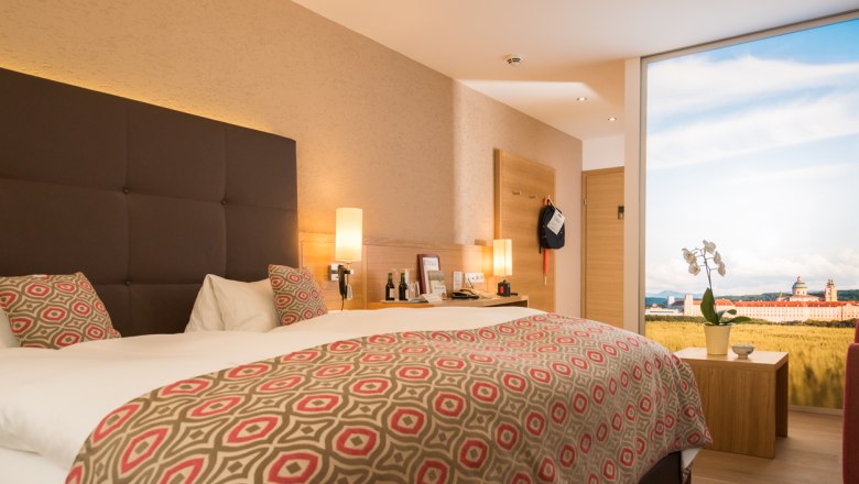Donauhof room example, © Marcella Wallner Modern hotel room with double bed, stylish lamps and large window with landscape view.