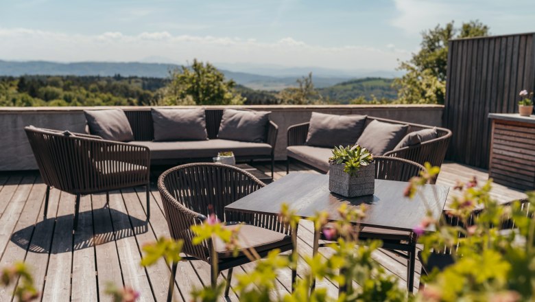 Wirtshaus mit regionalem Weitblick, © Niederösterreich Werbung/Daniela Führer Terrasse mit Sitzmöbeln und Pflanzen, im Hintergrund eine weite Landschaft.