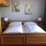 Room example vacation at the Jauerling, © Romana Wiener Cozy bedroom with wooden furniture, double bed, two deer paintings on the wall and a ladder to a loft bed.