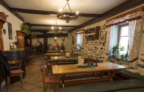 12b4566, © Josef Salomon Gemütlicher Gastraum mit Holztischen und Steinwänden.