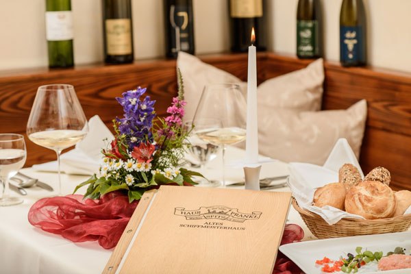 Old shipmaster's house, © Best of Wachau_Rita Newman Elegant table setting with menu, candle, flowers and bottles of wine in the background.
