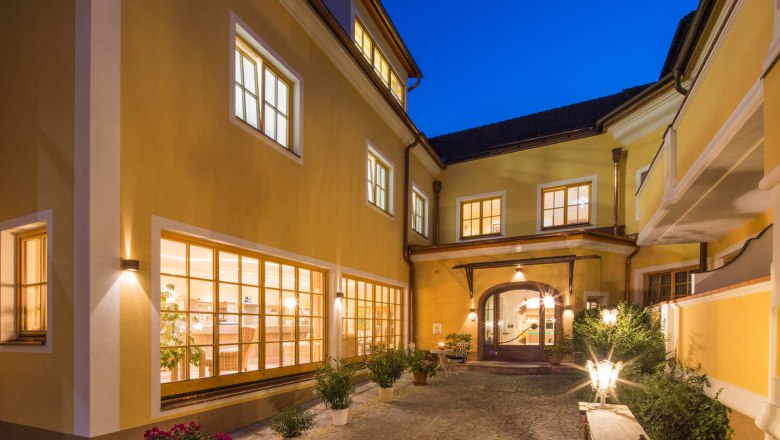 Hotel-Restaurant "Zum Schwarzen Bären", © Lachlan Blair Innenhof des Hotel Zum Schwarzen Bären mit beleuchteten Fenstern und Pflanzen bei Nacht.