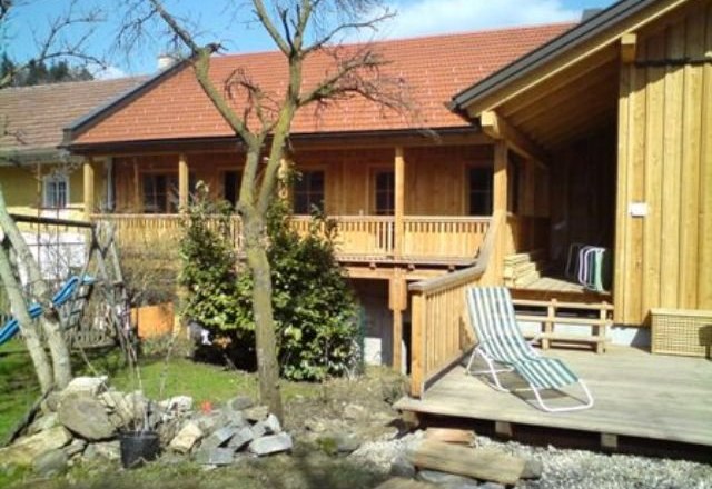 Pferdehof Kranzer, © Maria Kranzer Holzgebäude mit Terrasse und Garten im Vordergrund.