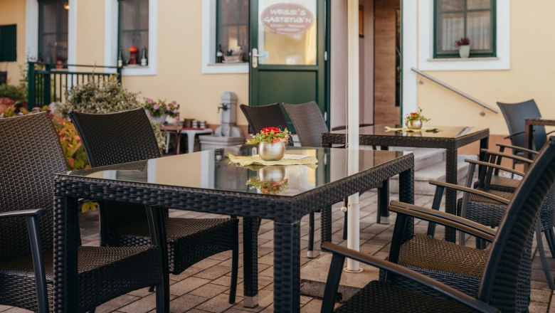 Guest garden & own apricot garden, © Niederösterreich Werbung/Daniela Führer Cozy outdoor area of an inn with rattan furniture and flowers.