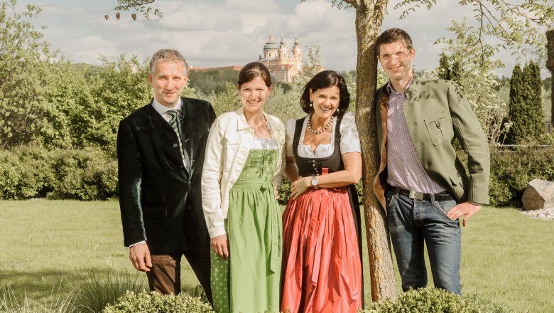 Host family Pichler, © Rita Newman The Pichler family in traditional dress stand outside in front of a tree, with Sift Melk in the background