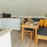 Appartement 2, © Ines Nejedly Gemütliche Essecke in einem modernen Appartement mit Holztisch, Eckbank und gelben Kissen.
