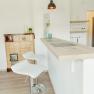 Apartment 2, © Ines Nejedly Modern kitchen with bar counter and two white bar stools, next to a traditional oven.
