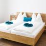 Gästezimmer, © Familie Martin Modernes Gästezimmer mit Doppelbett, weißen Bettdecken und blauen Kissen.