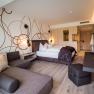 Zimmerbeispiel, © Alexander Pfeffel Photography Modern eingerichtetes Hotelzimmer mit Doppelbett, Sofa und Schreibtisch.