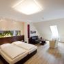 Room example, © Prankl Modernly furnished hotel room with double bed, sofa, armchair and TV.