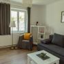 Apartment 1, © Ines Nejedly Bright living room with gray sofa, armchair, floor lamp and white furniture.