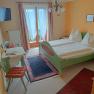 Zimmerbeispiel im Haus Sundl, © Margit Siebenhandl Zimmer mit grünem Doppelbett und Tisch mit Stuhl