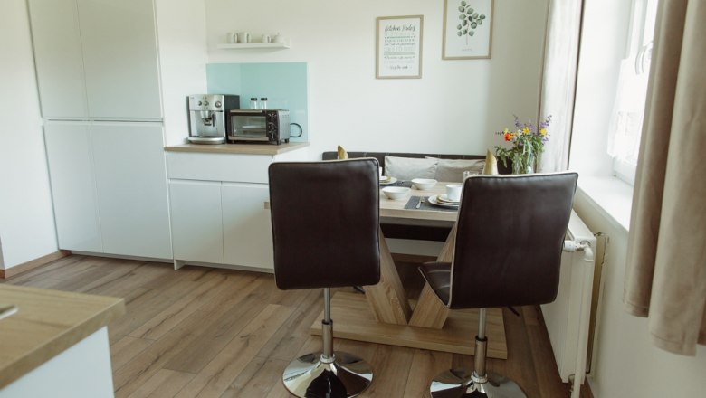 Appartement 1, © Ines Nejedly Moderne Küche mit Esstisch, Stühlen und Geräten.