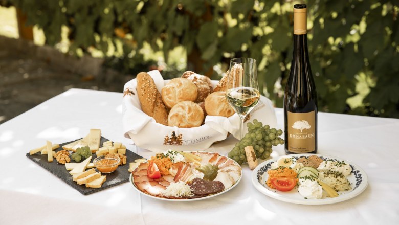 Heurigenjause_Christoph Donabaum, © Nimo Zimmerhackl Heurigenjause mit Brot, Käse, Aufschnitt, Wein und Trauben auf einem Tisch.