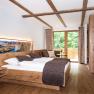 Zimmer im Kalmuckdesign, © Martina Siebenhandl Modernes Hotelzimmer mit Holzmöbeln, großem Bett und Balkon mit Blick ins Grüne.