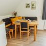 Appartement 2, © Ines Nejedly Essbereich mit Holztisch, Stühlen und Eckbank, gedeckt mit Geschirr, Blumenstrauß und Dekoration an der Wand.