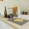Appartement 2, © Ines Nejedly Moderne Küche mit Bartresen, Weinglas und Flasche.