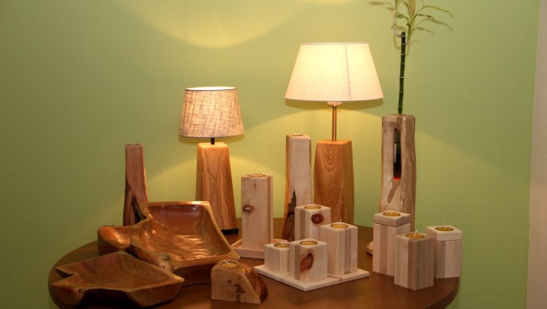 Holzhandwerk Täubl, © Fa. Täubl Holzhandwerk mit Lampen und Kerzenhaltern auf einem Tisch.