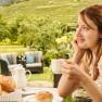 Weingut Donabaum, © Rita Newman Frau genießt Kaffee im Freien mit Blick auf Weinberge.