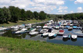 Boats in the Emmersdorf marina, © Amt der NÖ Landesregierung, Abt. Wasserwirtschaft /Ing. Werner Hauer Boats in the Emmersdorf marina, surrounded by green trees and blue skies.