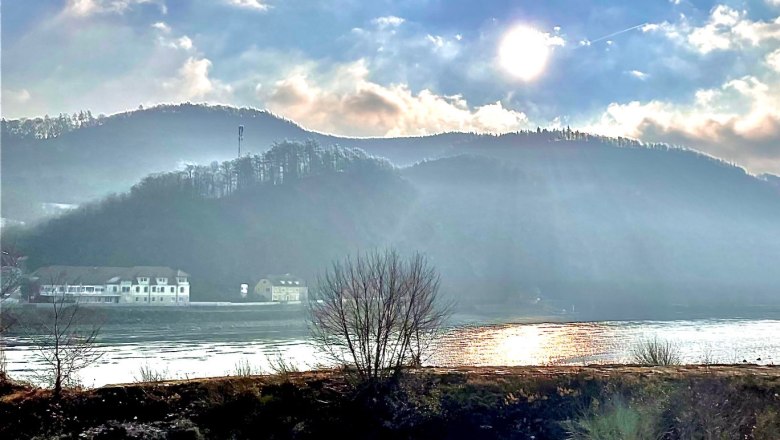 View from Haus Donau, © Haus Donau, Hr. Benesics Sunbeams over a river with hills in the background.