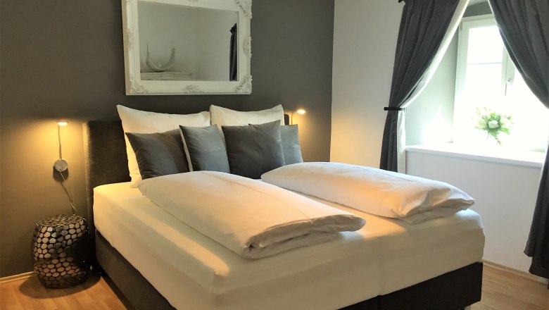 holiday-apartment-1000-eimerberg, © Gritsch Modern bedroom with double bed, gray walls and decorative mirror.