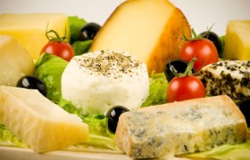 Biokäserei Roland Berger, © Biokäserei Roland Berger Verschiedene Käsesorten auf einem Holzbrett mit Tomaten und Oliven.