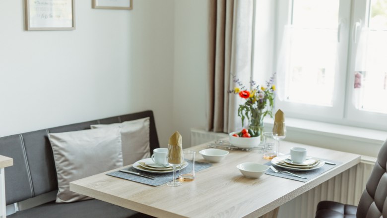 Appartement 1, © Ines Nejedly Essbereich in einem modernen Appartement mit gedecktem Tisch und Blumen.