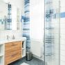 Bathroom, © Georg Pomassl Modern bathroom with wooden cabinet, mirror, shower curtain and tiles.