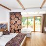 Familienzimmer, © Martina Siebenhandl Ein modernes Familienzimmer mit Holzboden, zwei Betten, großen Fenstern und dekorativen Holzelementen.