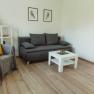 Apartment 1, © Ines Nejedly Modern living room with gray sofa, armchair, white coffee table and wooden floor.