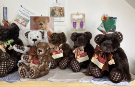 Bärenfamilie, © Elisabeth Seitner Eine Sammlung von Plüschbären mit karierten Schleifen auf einem Tisch.