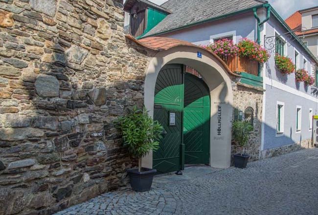 12b1196300, © Josef Salomon Historisches Gebäude mit grünem Tor und Blumen.