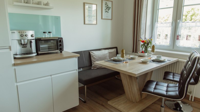 Appartement 2, © Ines Nejedly Moderne Küche mit Esstisch, Stühlen und Kaffeemaschine.