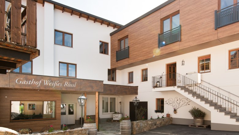 Exterior view, © Martina Siebenhandl Exterior view of an inn with wooden and white facades, staircase and decorations.