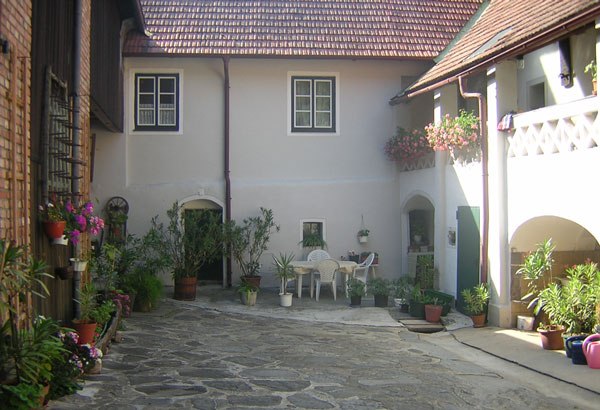 Haus Stierschneider, © Familie Stierschneider Innenhof eines traditionellen Hauses mit Pflanzen und Sitzbereich.