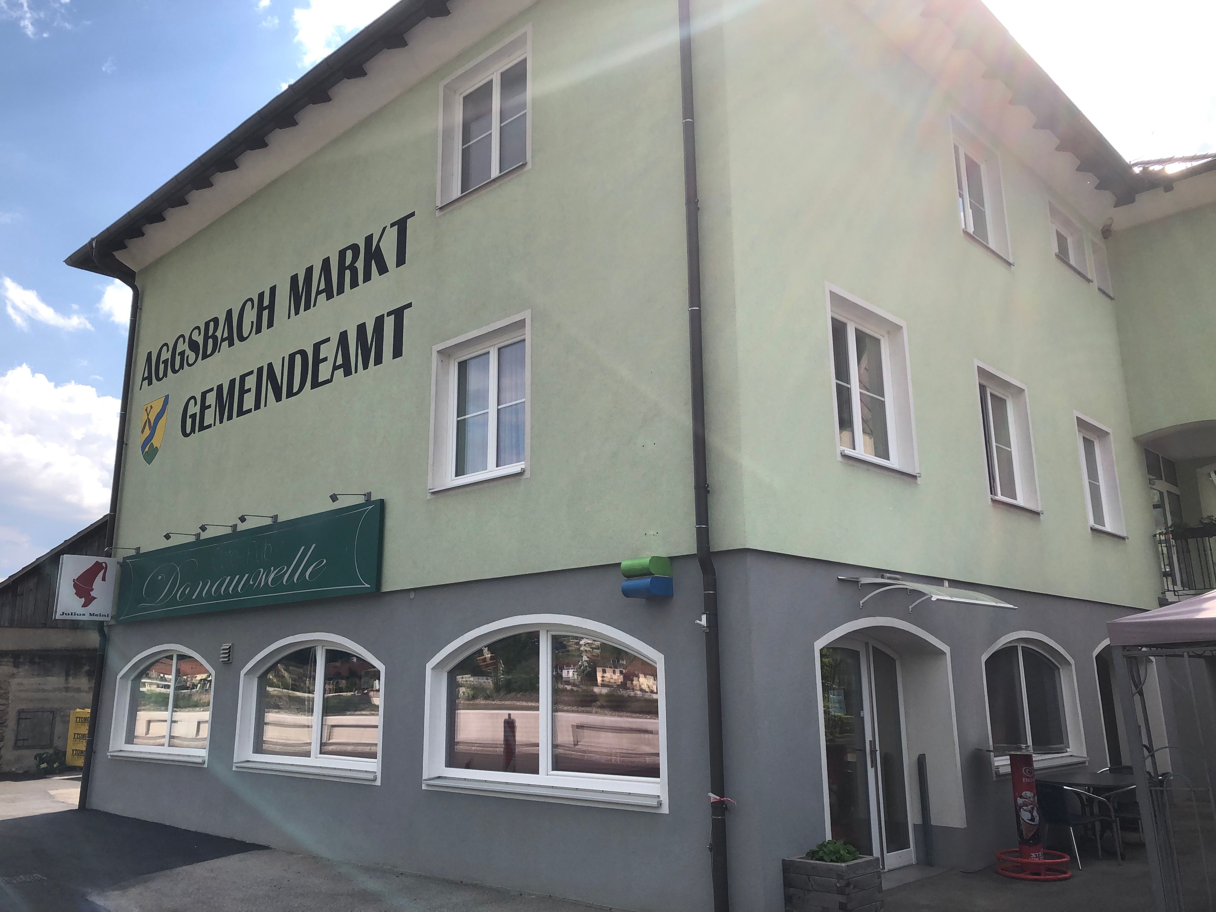 Grünes Gebäude mit Aufschrift 'Aggsbach Markt Gemeindeamt' und Café Donauwelle.