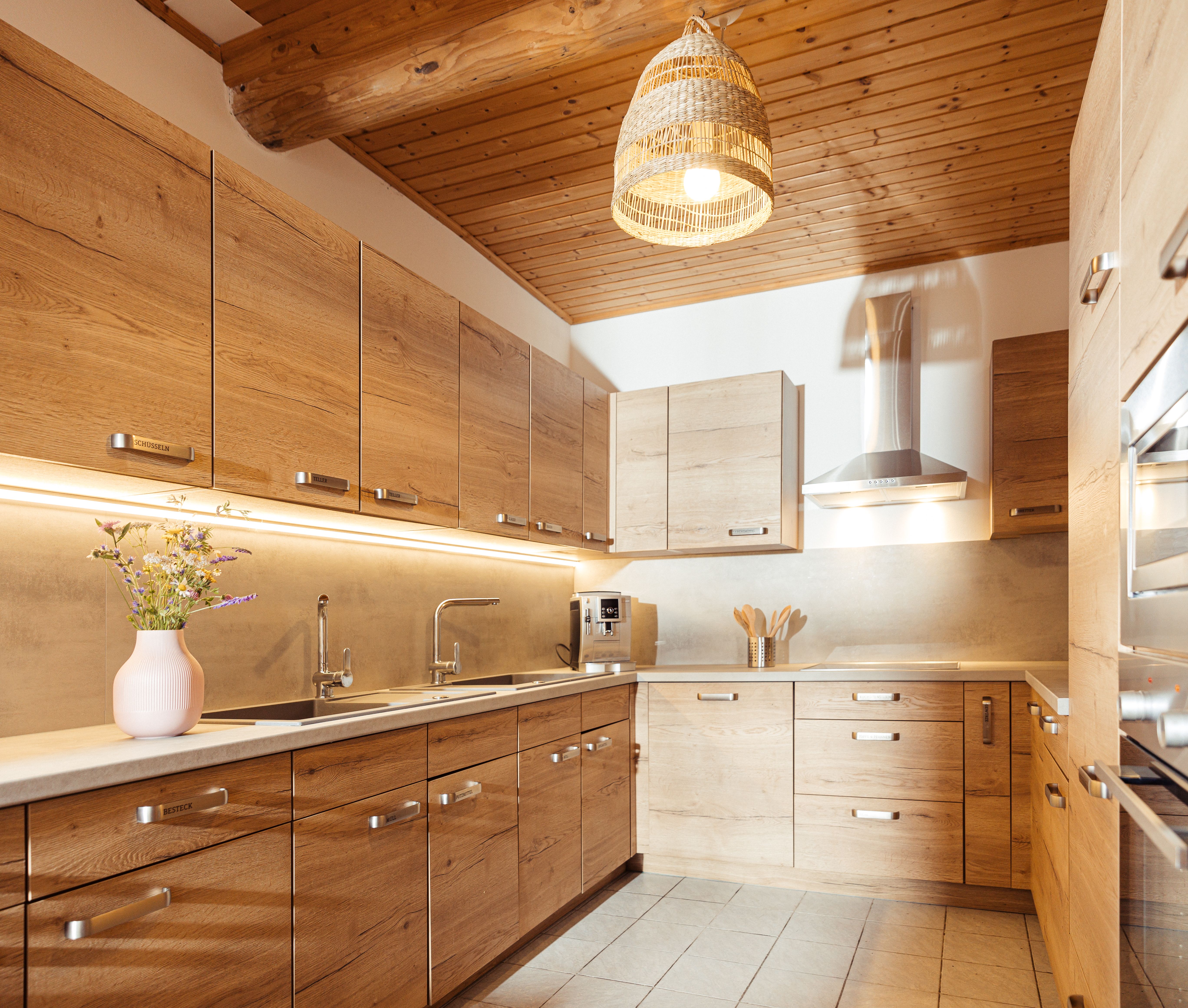 Eine moderne Küche in Holzoptik mit weicher Beleuchtung.