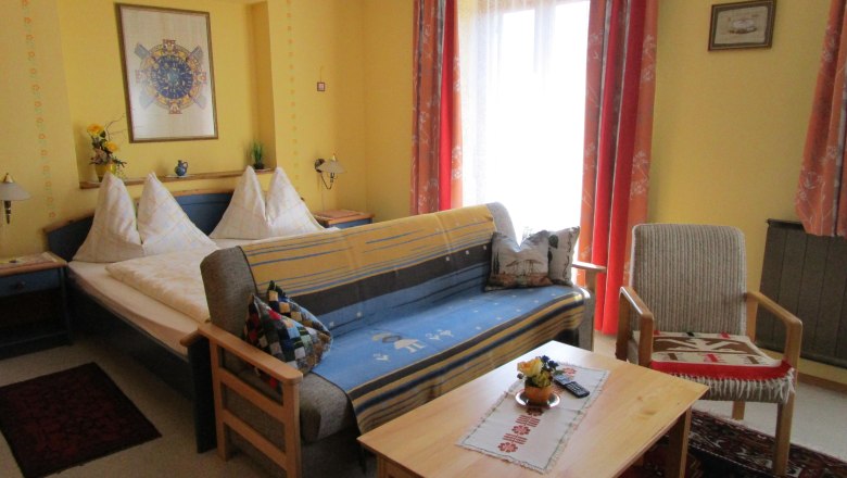 Zimmer mit Doppelbett und Couch mit Tisch im Vordergrund