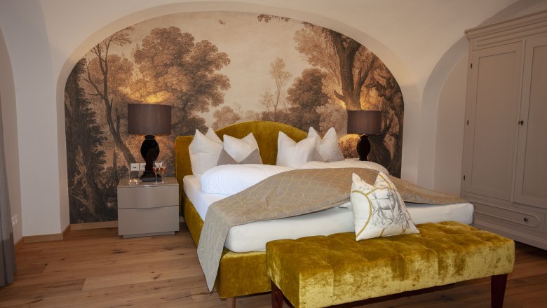 Elegant suite with yellow bed, wall painting and wooden floor in Luberegg Castle