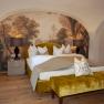 Elegant suite with yellow bed, wall painting and wooden floor in Schloss Luberegg