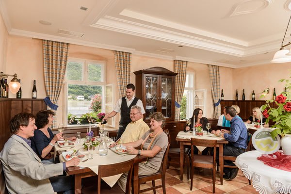 A cozy restaurant with guests dining at tables. A waiter serves the guests. Window with a view of a green landscape.