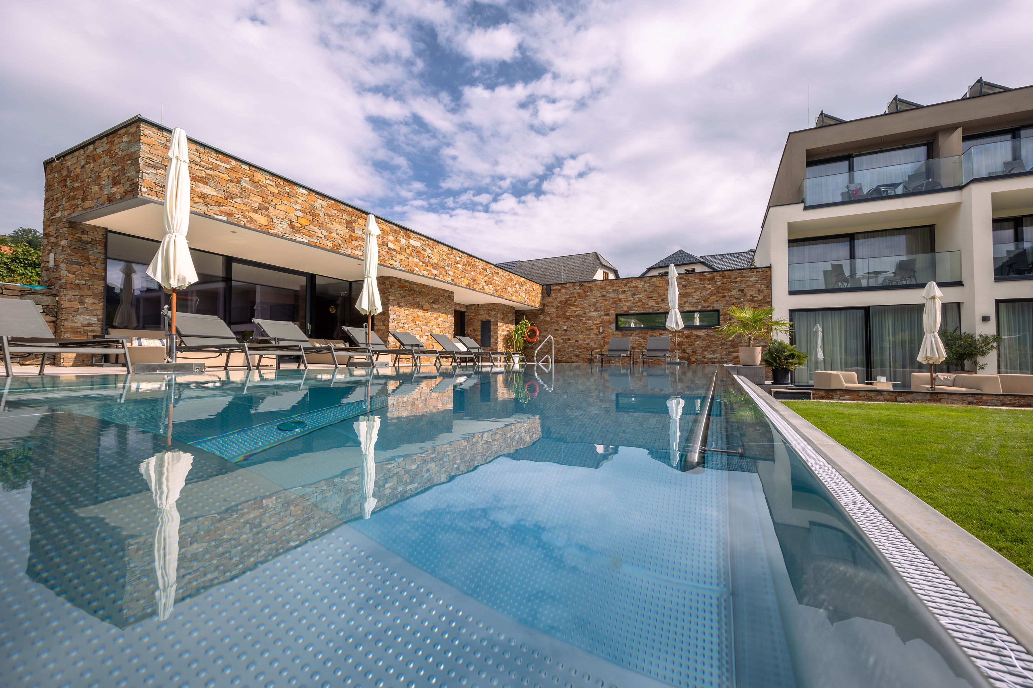 Außenansicht eines modernen Hotels mit Pool und Liegestühlen.