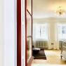 Bright bedroom with wooden floor, white curtains and a chandelier.