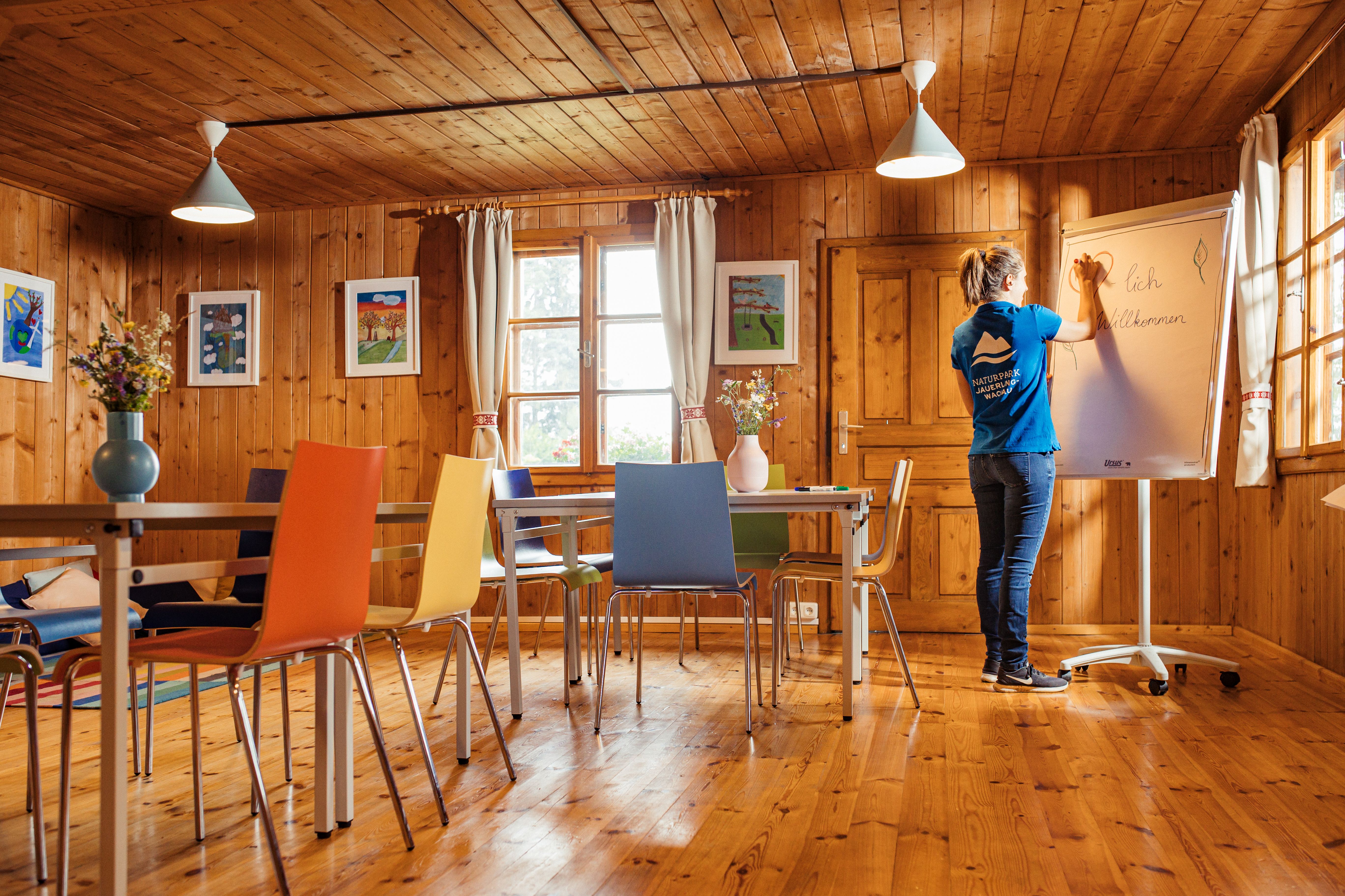 Ein Großer Seminarraum mit Whiteboard, Tisch und Sesseln.